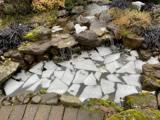 shatted ice on a large garden pond surrounded by rocks
